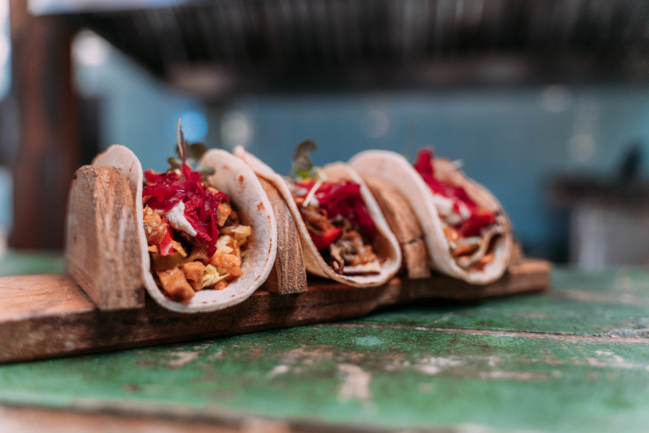 Three veegan tacos on a wood serving board. 